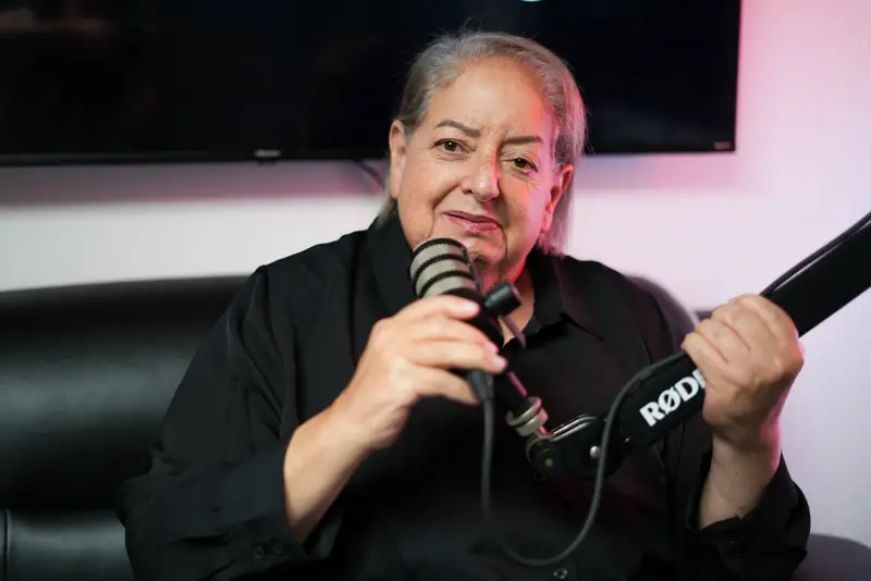 Sharon Tabak speaking into a microphone in a podcast studio